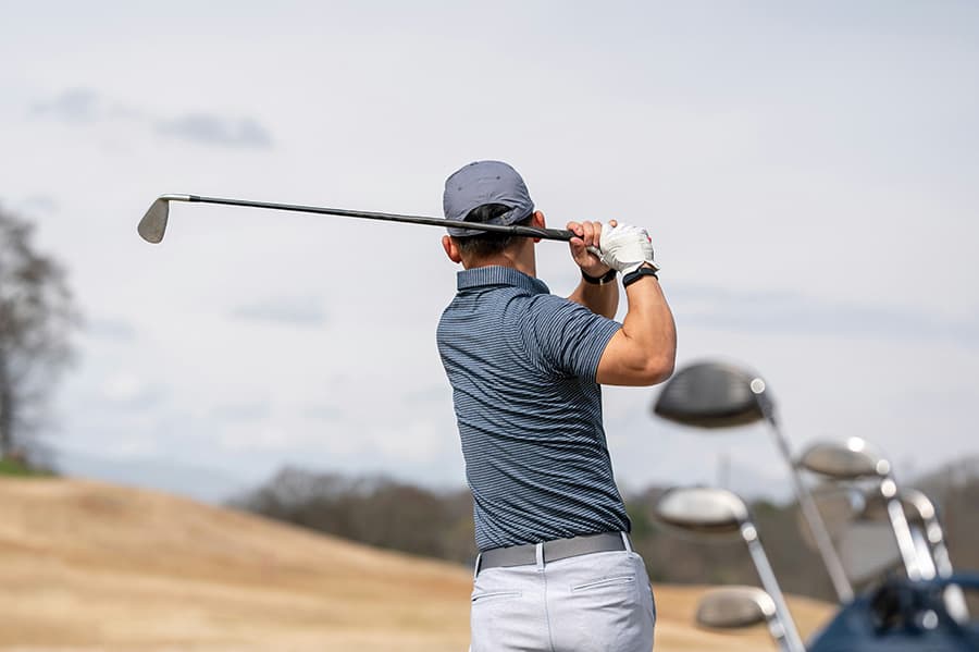 Golfer mid-swing at a chamber golf tournament
